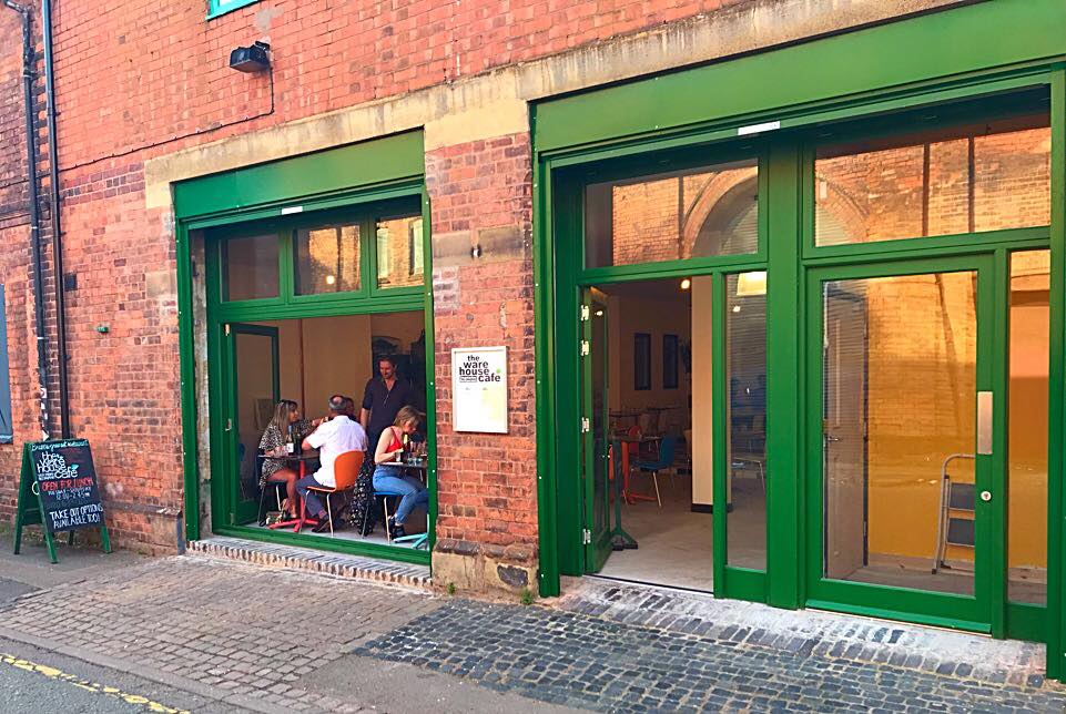 A photo of the outside of the Warehouse Cafe with customers enjoying their meals visible through the open windows